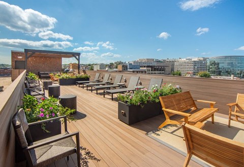 a roof top patio with wooden benches and plants