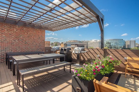 a roof deck with tables and benches and a pergola