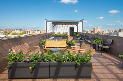a roof terrace with tables and chairs and a city in the background