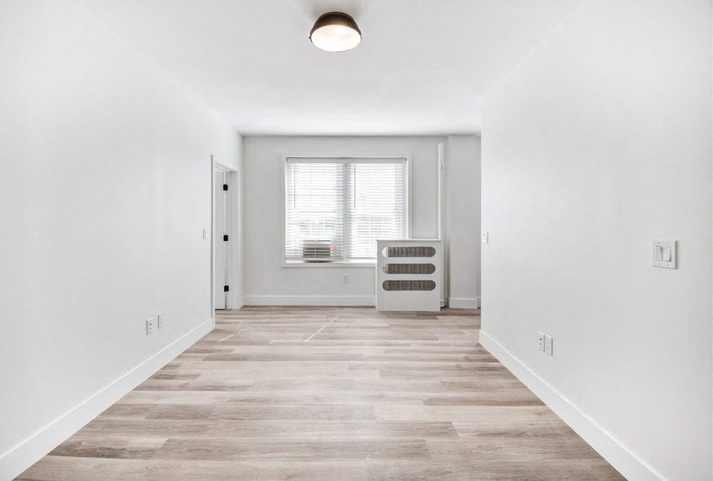 an empty room with white walls and a window and a radiator
