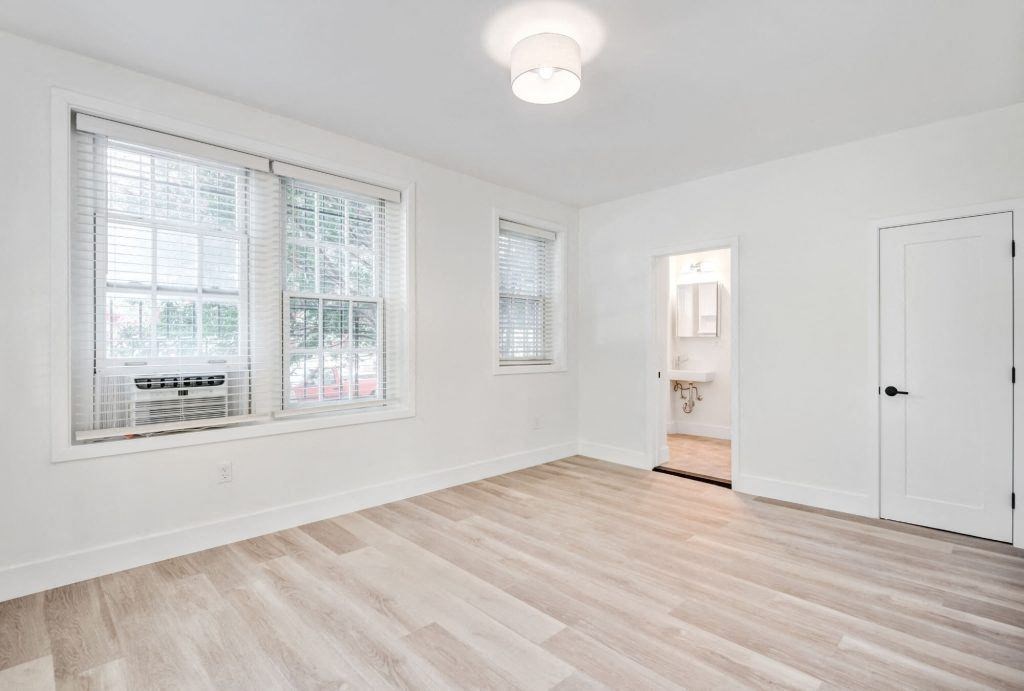 an empty living room with a window and a door to a bathroom