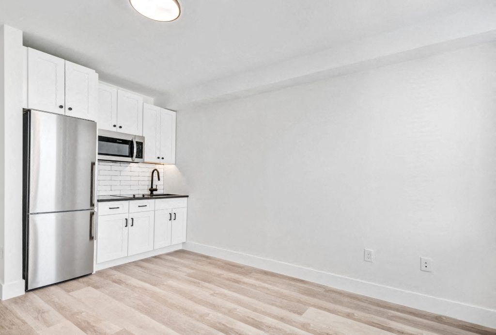 a kitchen with white cabinets and a stainless steel refrigerator
