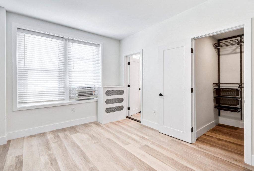 a bedroom with a closet and a window and a wood floor