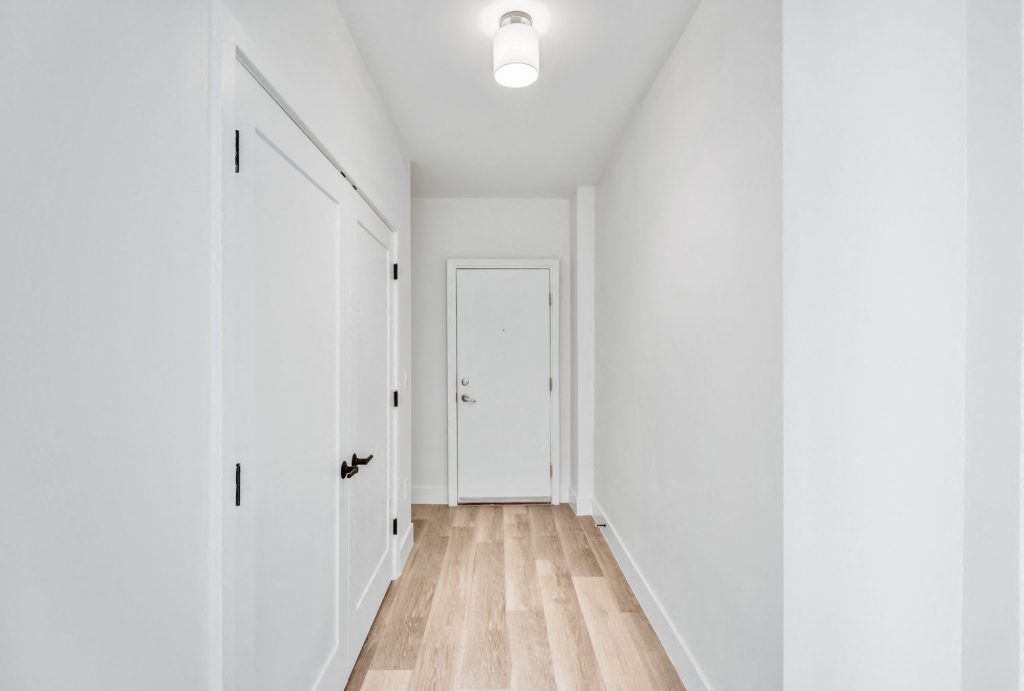 a renovated hallway with white walls and wood floors