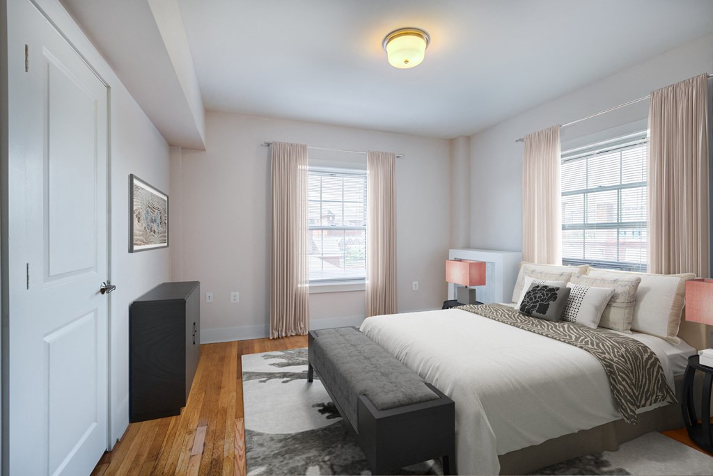 a bedroom with a bed and a dresser and two windows