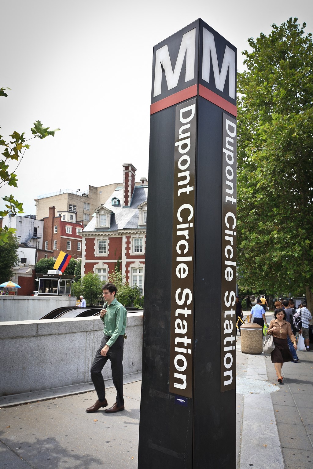 a man talking on a cell phone next to a sign