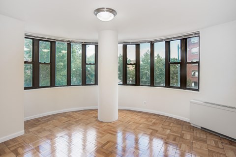 an empty living room with windows and wood flooring