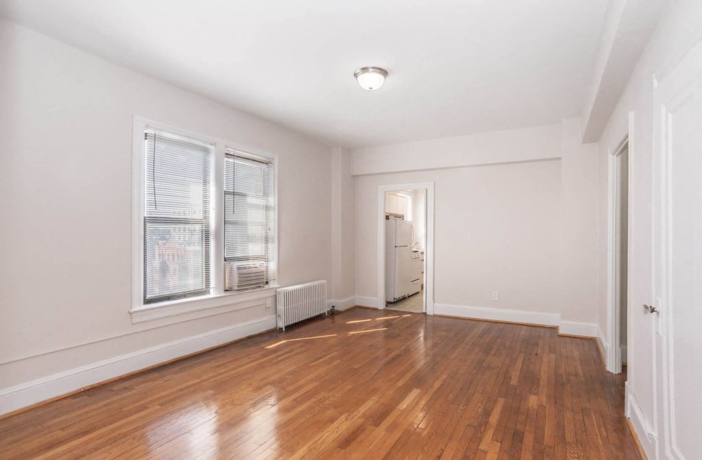an empty living room with hardwood floors and a window