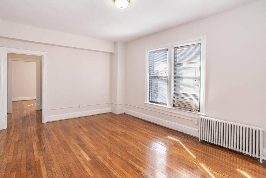 an empty living room with wood floors and a window
