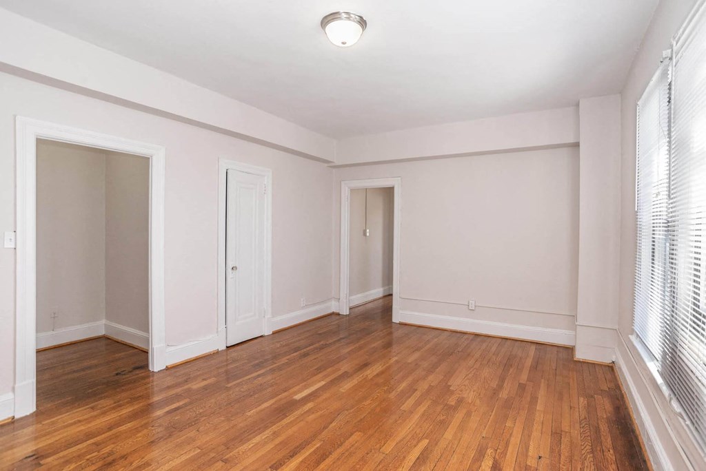 an empty living room with wood floors and white walls