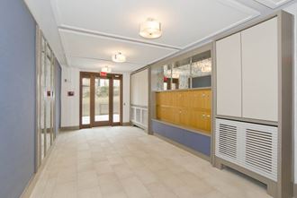 a long hallway with a door at the end and cabinets on the side of the hallway