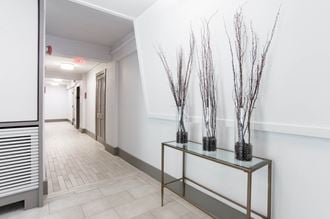 a hallway with a table with three vases with branches on it
