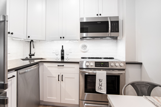 a white kitchen with stainless steel appliances and white cabinets
