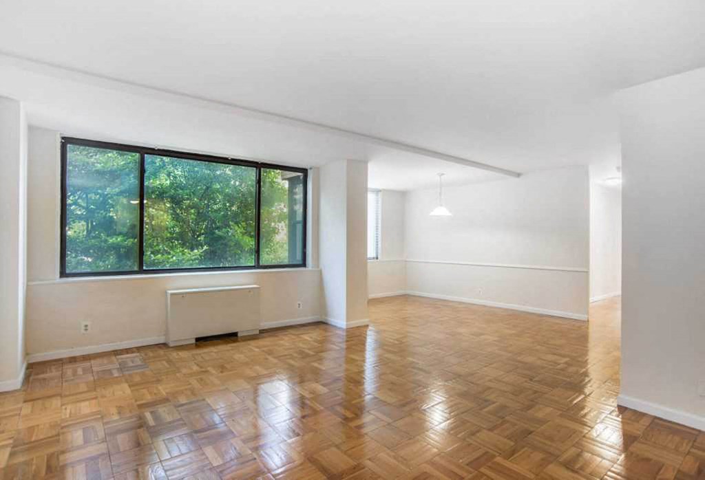 an empty living room with a large window and wooden floors