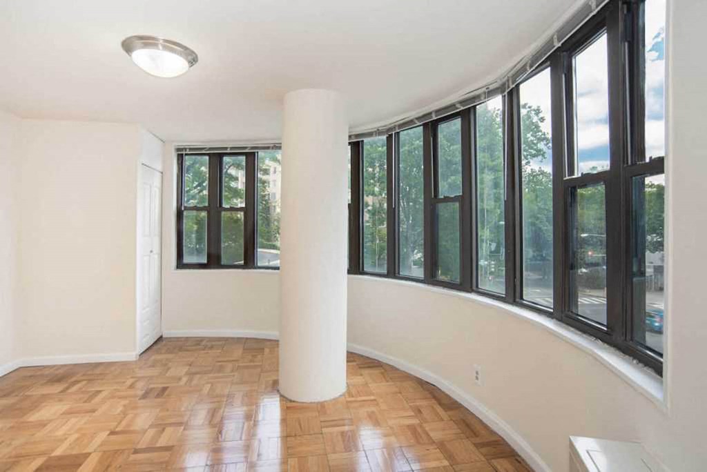 an empty living room with a large window and a rounded column