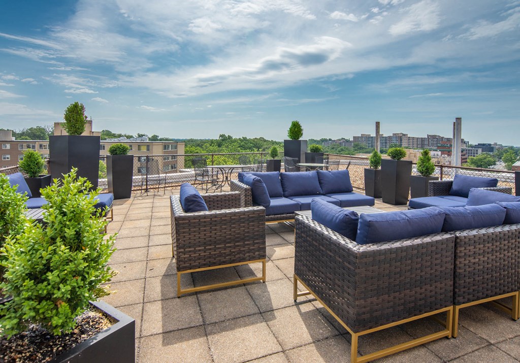 a roof top patio with furniture and a city in the background