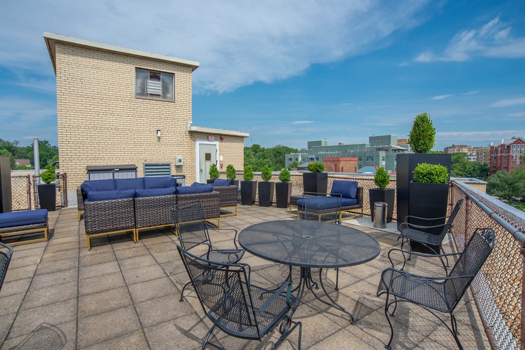 a roof top patio with furniture and a city in the background