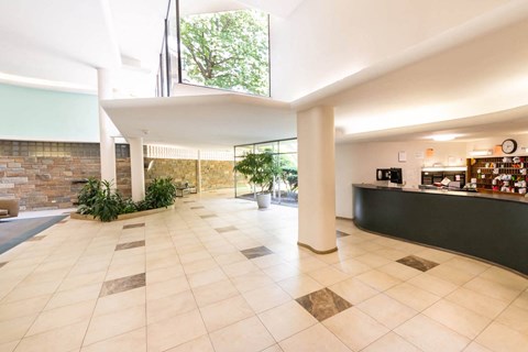 A spacious lobby with a reception desk and a brick wall.