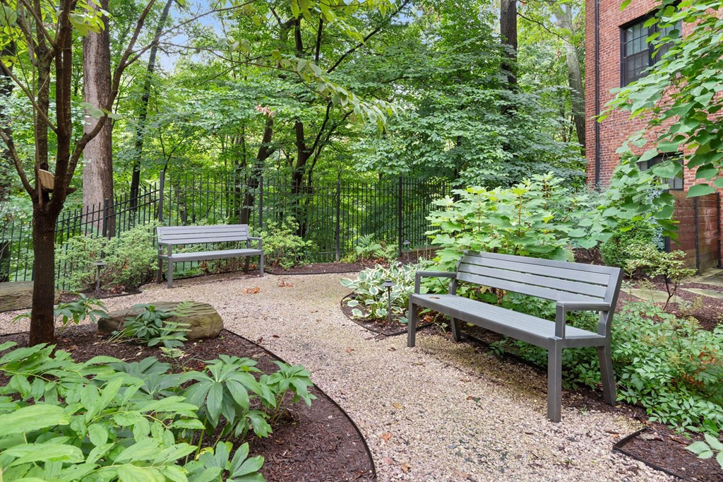 two benches in a garden next to a brick building