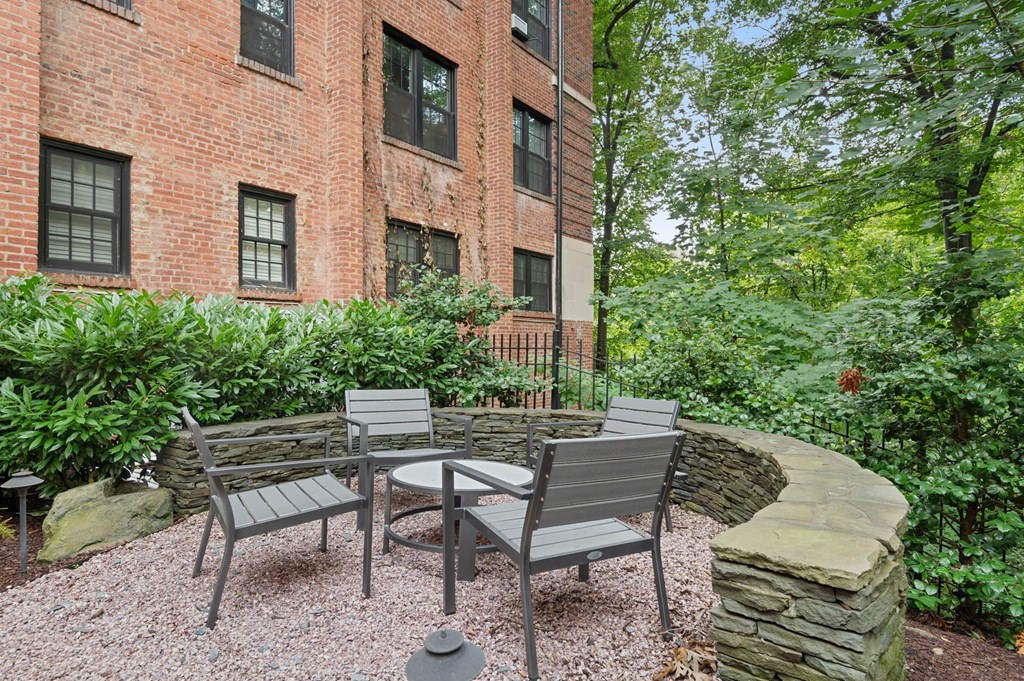 a patio with chairs and a table in front of a brick building