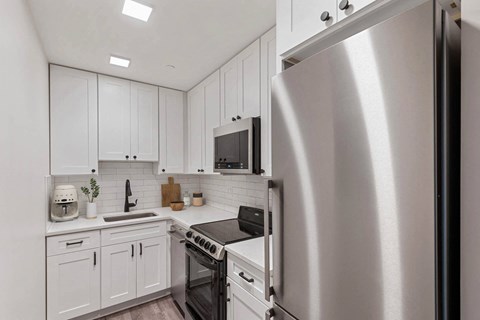 a white kitchen with stainless steel appliances and white cabinets