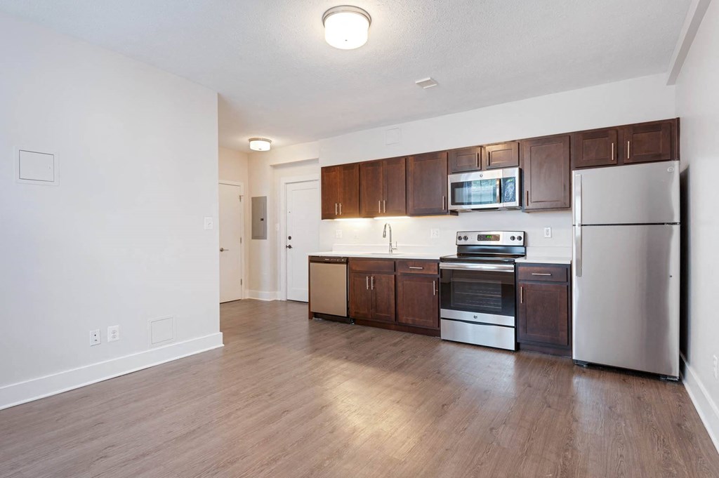 an empty kitchen with wood flooring and stainless steel appliances