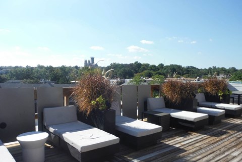 a roof top deck with furniture and a city in the background