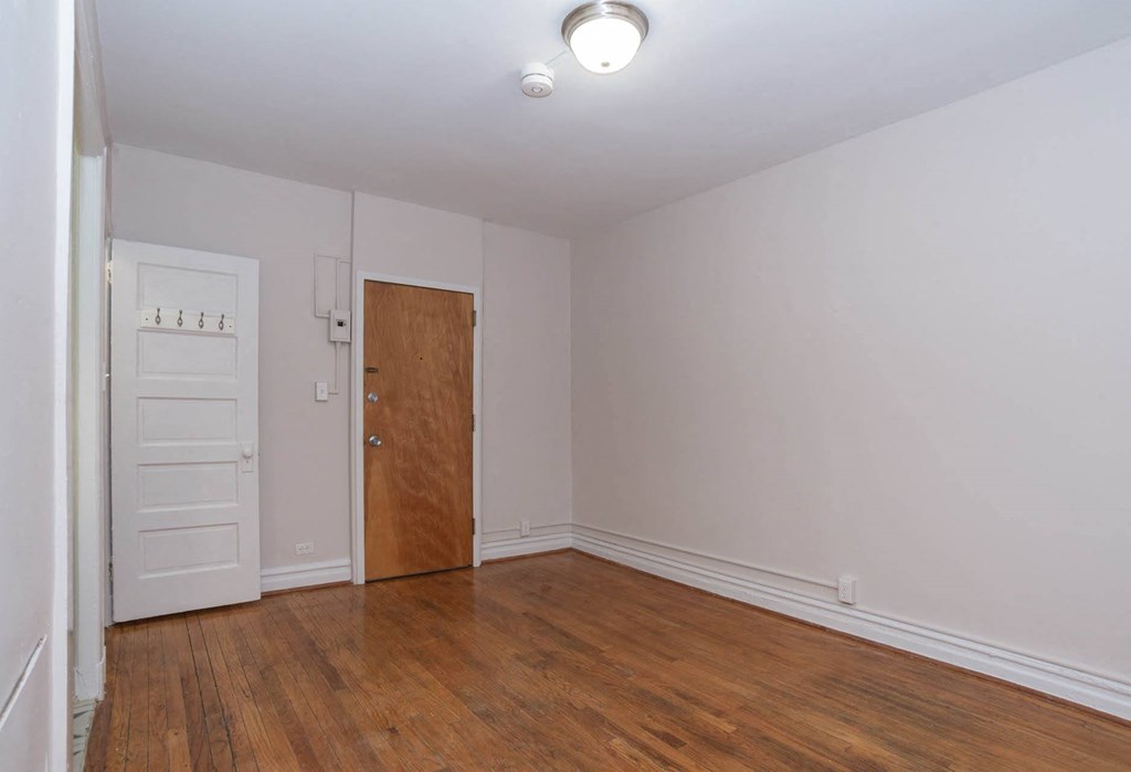 an empty living room with a wooden floor and a white door