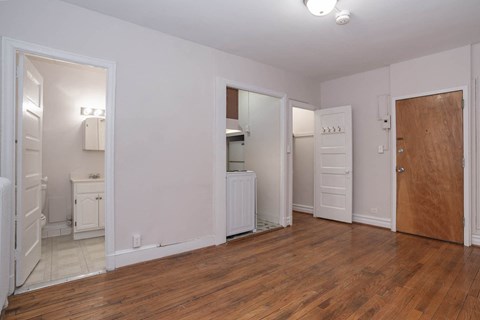 a living room with wood floors and a door to a bathroom