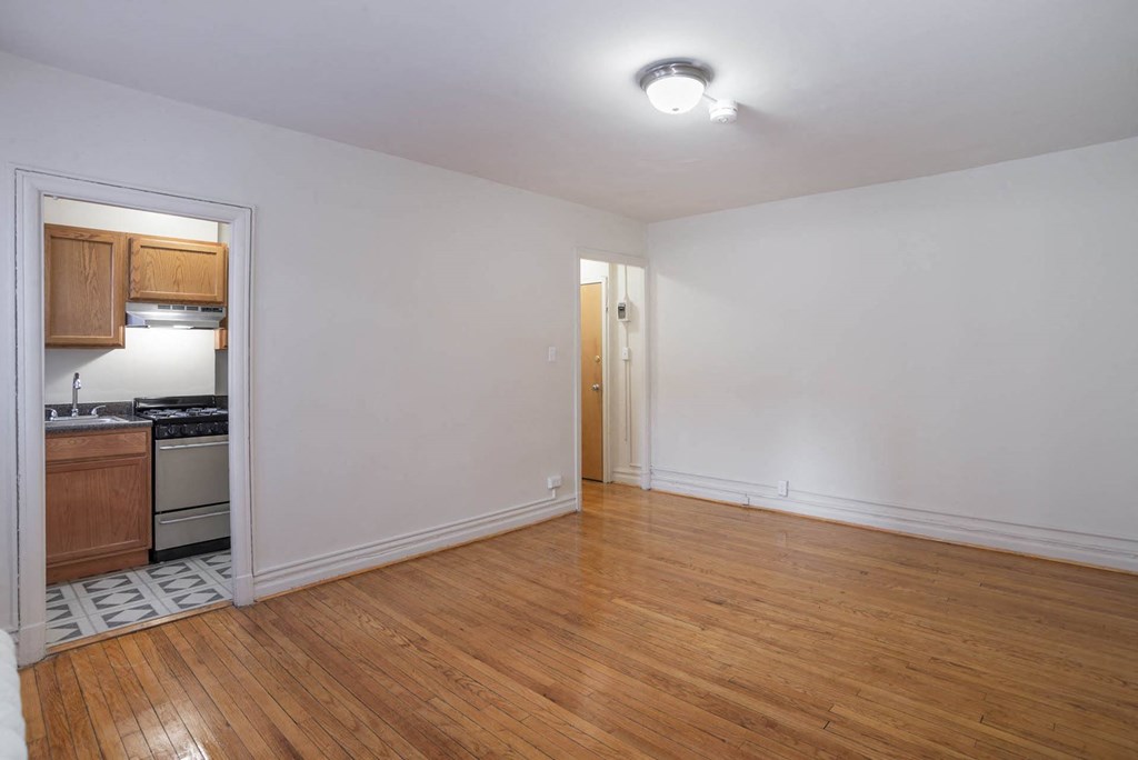 an empty living room and kitchen with wood floors and white walls