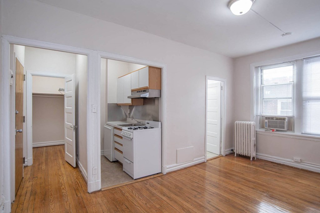 an empty living room with a kitchen and a window