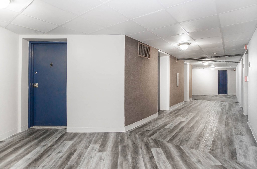 a hallway with white walls and a blue door
