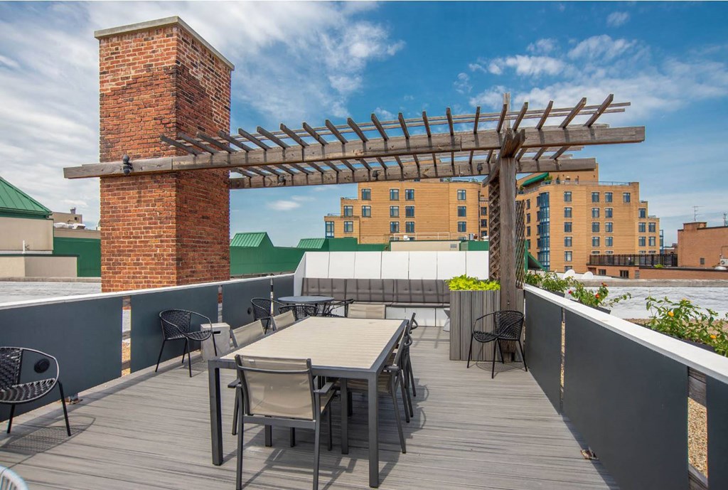 a roof terrace with tables and chairs and a pergola