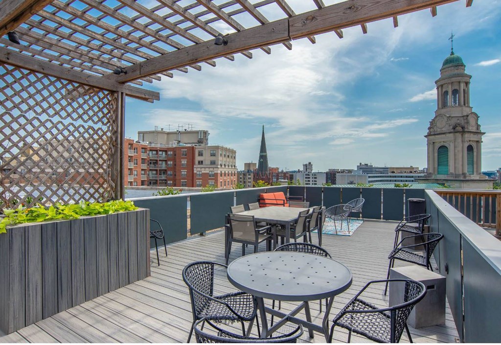 a roof deck with tables and chairs and a view of the city