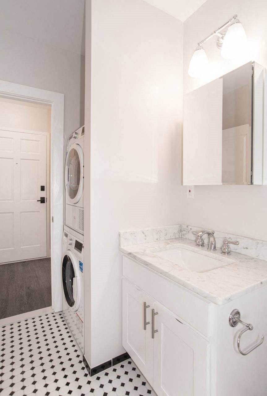 a white bathroom with a washing machine and a sink