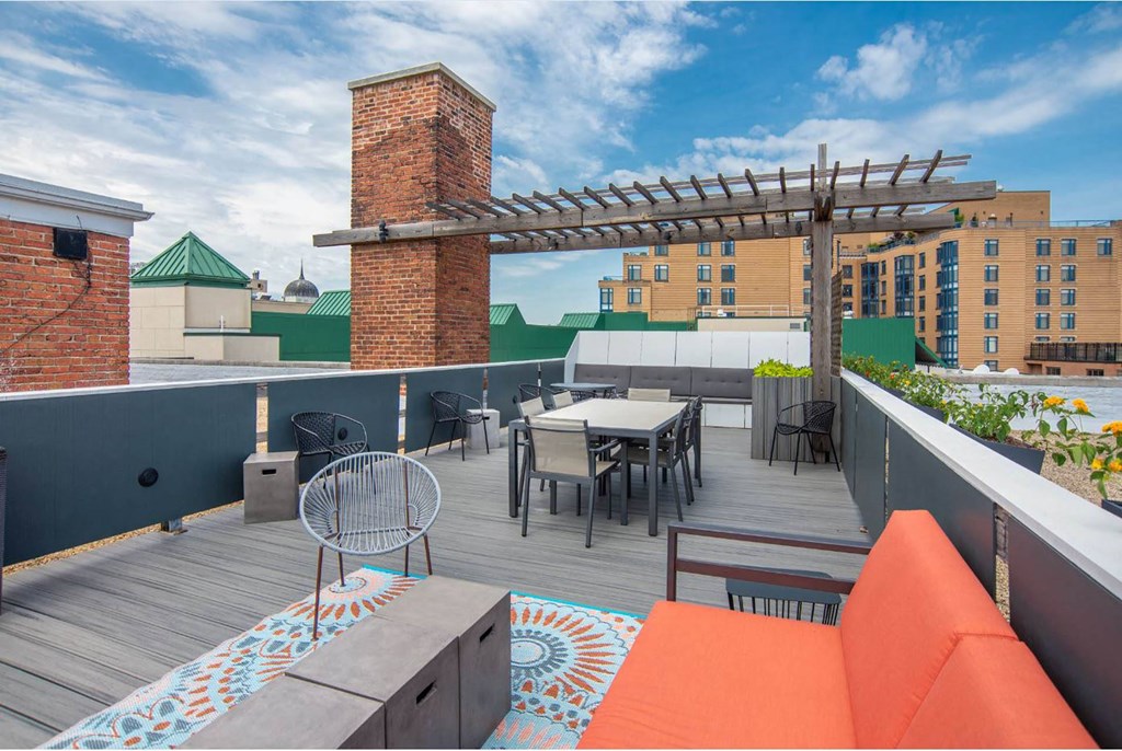 a rooftop patio with tables and chairs and a building in the background