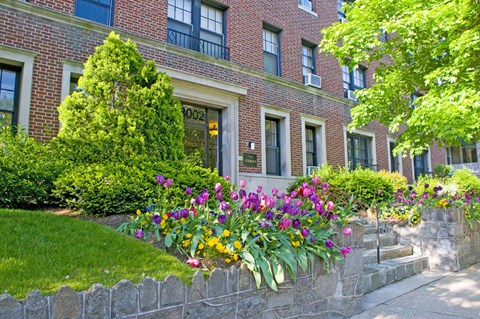 a flower garden in front of a brick building
