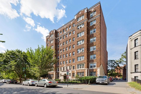 view from the street of an apartment building with cars parked in front