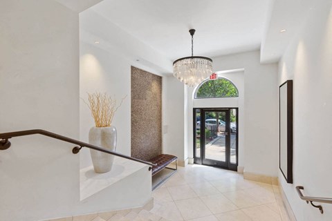 a foyer with a staircase and a chandelier   and a door