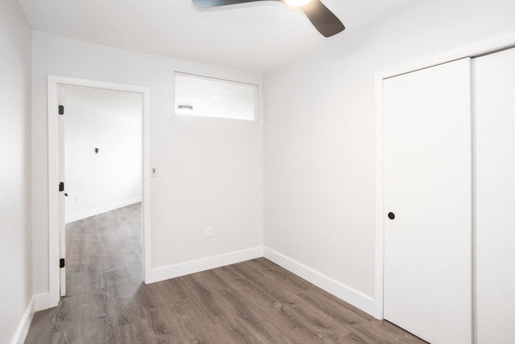 a bedroom with white walls and a wooden floor