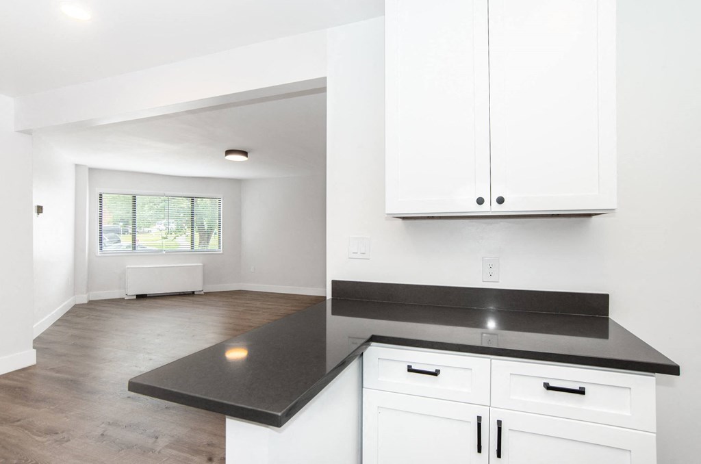 a kitchen with white cabinets and black countertops