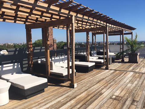 a rooftop deck with lounge chairs and a pergola