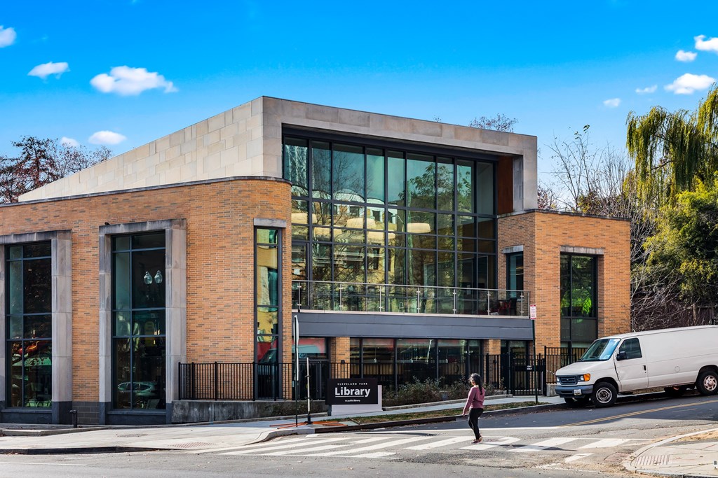 a building with large glass windows and a woman crossing the street