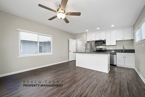 A spacious kitchen with white cabinets and a ceiling fan.