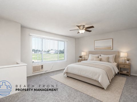 A bedroom with a large bed, a window with a view of the beach, and a ceiling fan.