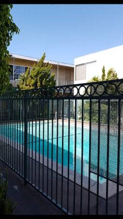 a swimming pool behind a black fence with a building in the background