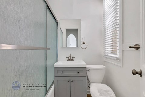 A bathroom with a toilet, sink, and mirror.