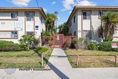 a sidewalk in front of two apartment buildings with a gate