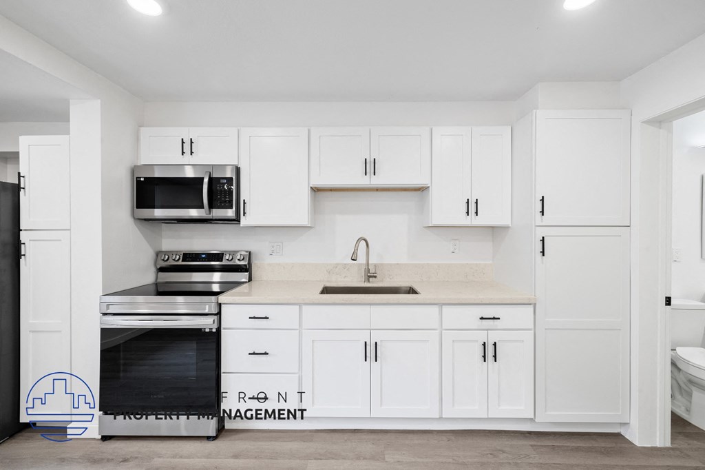 A kitchen with white cabinets and appliances.