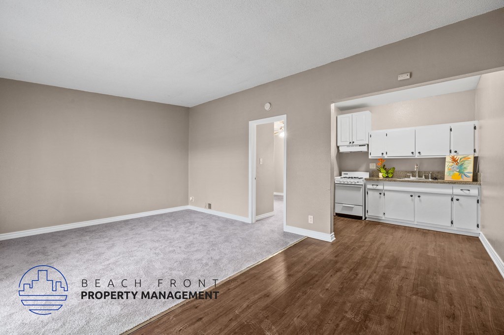 a living room and kitchen with white cabinets and wood flooring